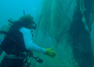SCUBA diver collecting drifting nets and ropes found in the water.
