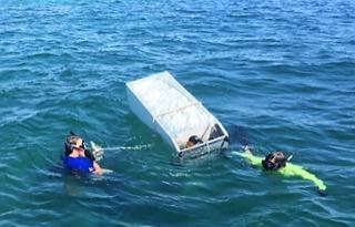divers pulling a floating refrigerator