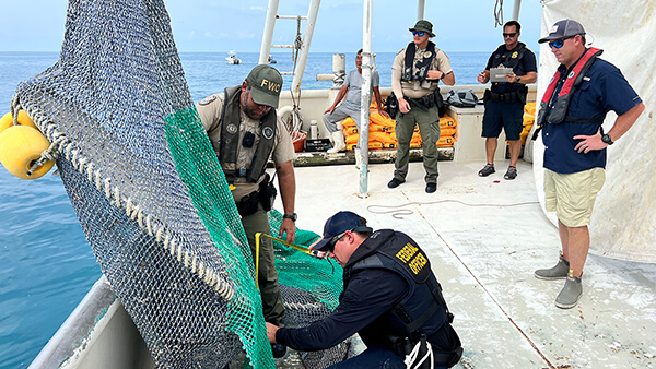 an officer checks a net on the deck of a boat