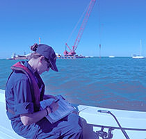 NOAA LT Rosemary Abbitt sitting on deck writing on a clipboard