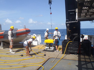 Photo of workers pull an ROV onto deck of ship.