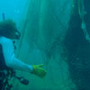 Photo of SCUBA diver collecting drifting nets and ropes found in the water.