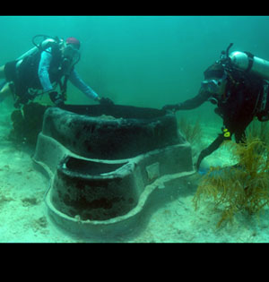 Divers lift a plastic mold off seafloor.